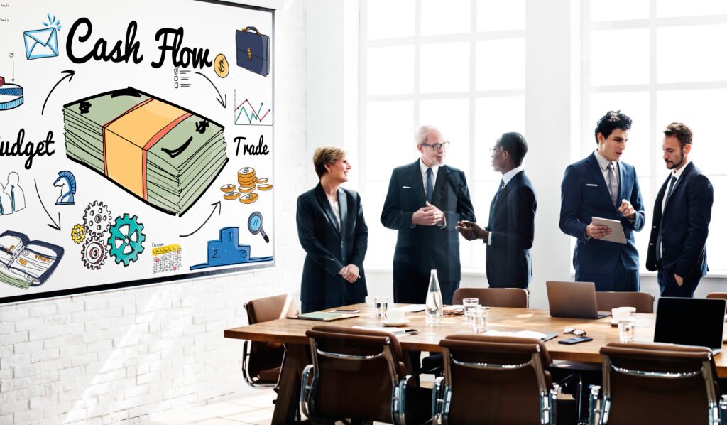 Business professionals discussing cash flow strategy in a meeting room, with a whiteboard showing financial concepts like money, budget, and trade.